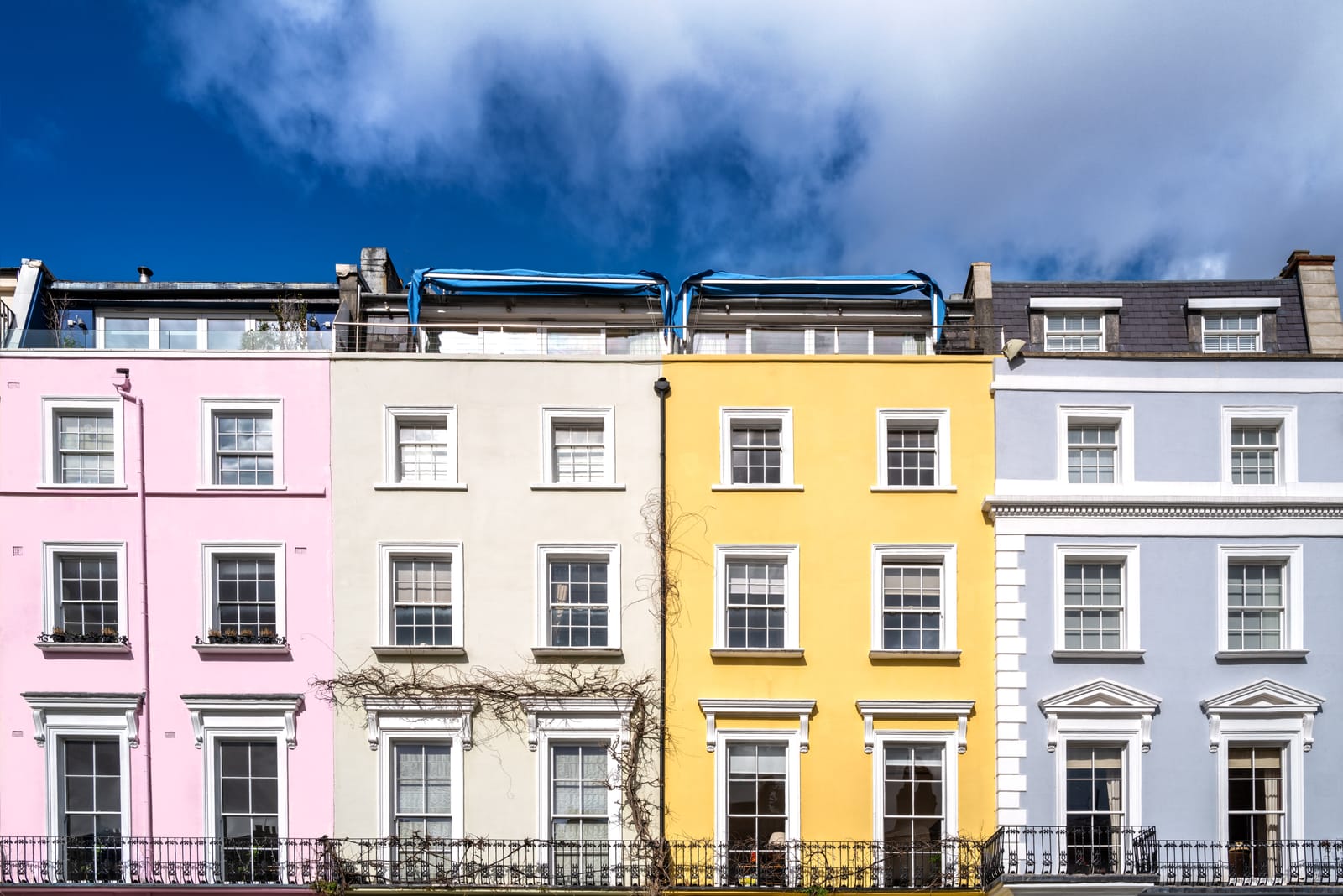 Pink, white, yellow and lilac terraced townhouses on a Notting Hill street