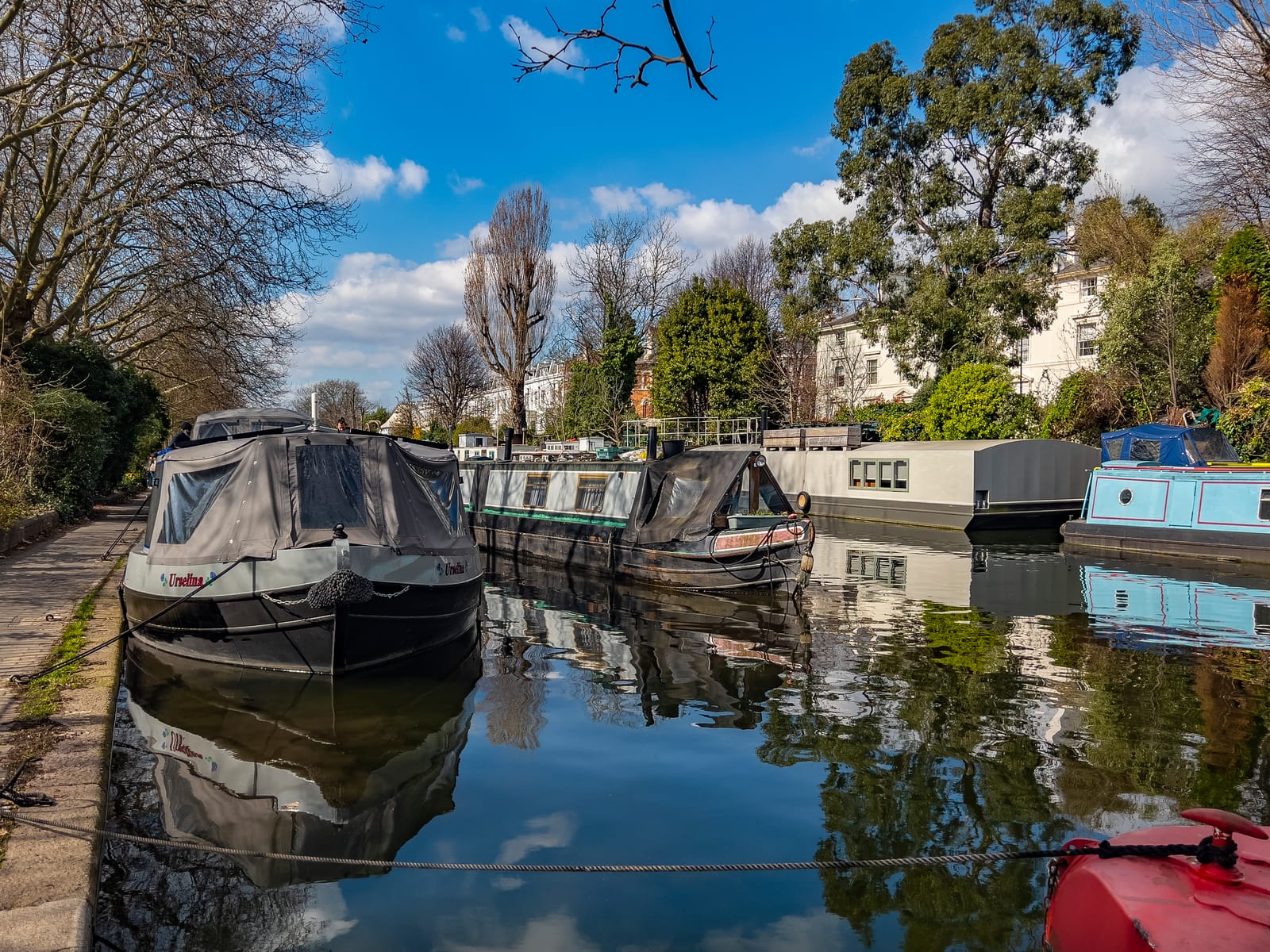 Narrowboats moored on the Regent's Canal at Little Venice, reflected in still water